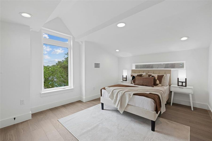 Bedroom featuring vaulted ceiling, wood finished floors, baseboards, and recessed lighting