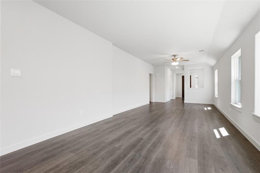 Spare room featuring dark wood-type flooring, a ceiling fan, and vaulted ceiling