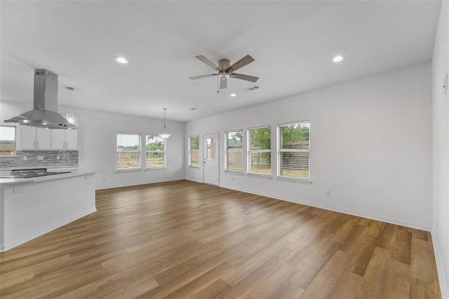 Bright living area with wood-finish flooring, recessed lighting, and a contemporary ceiling fan