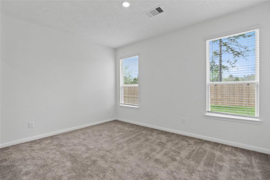 Relax and unwind after a long day in this impressive primary suite! This generously sized room offers carpet floor, warm-toned paint, high ceilings, and large windows with blinds for added comfort and tranquility.