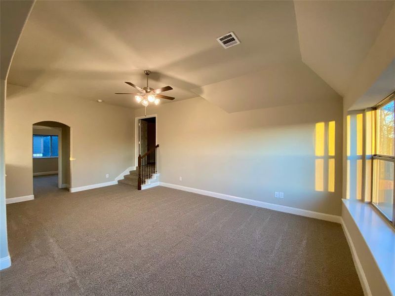 Gameroom with window seat, ceiling fan, and stairs leading to media room.