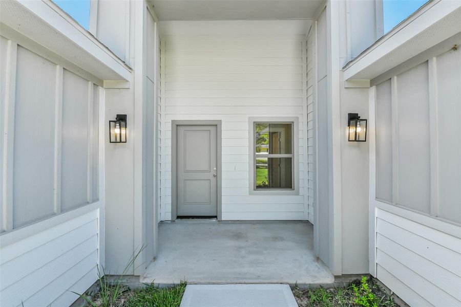 Covered front entry with modern lighting and clean architectural lines offering a welcoming first impression.