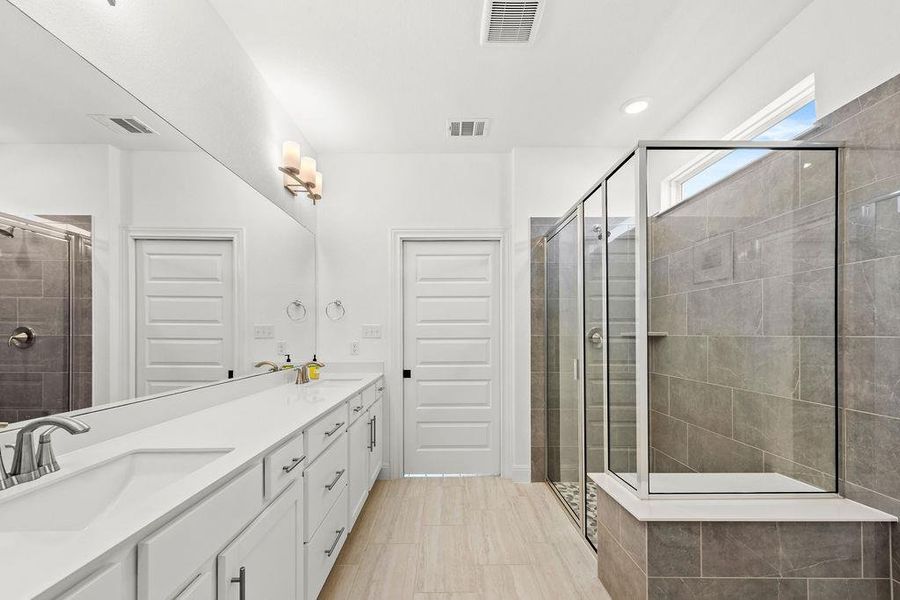 The primary bathroom features dual vanities on quartz countertops, with a large shower and dressing area.