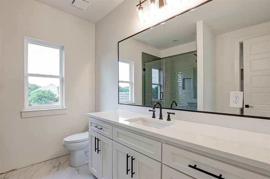 Full bath with marble look tiles, vanity, a shower stall, and plenty of natural light