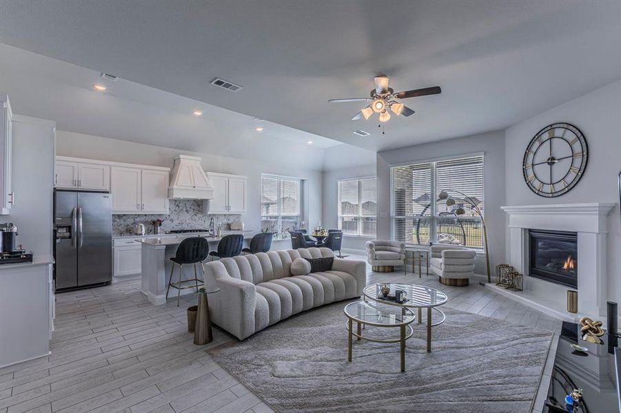 Living room featuring ceiling fan, wood tiled floors, a glass covered fireplace, recessed lighting, and lofted ceiling Living room featuring ceiling fan, wood tiled floors, a glass covered fireplace, recessed lighting, and lofted ceiling