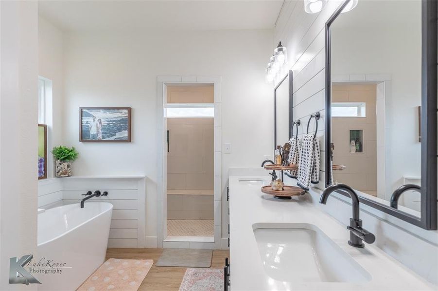 Full bath with a stall shower, a soaking tub, light wood-type flooring, and double vanity Full bath with a stall shower, a soaking tub, light wood-type flooring, and double vanity