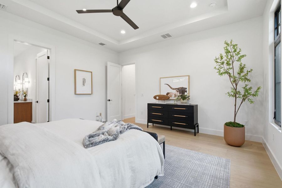 High ceilings and clean architectural lines define this serene bedroom sanctuary with light wood floors.