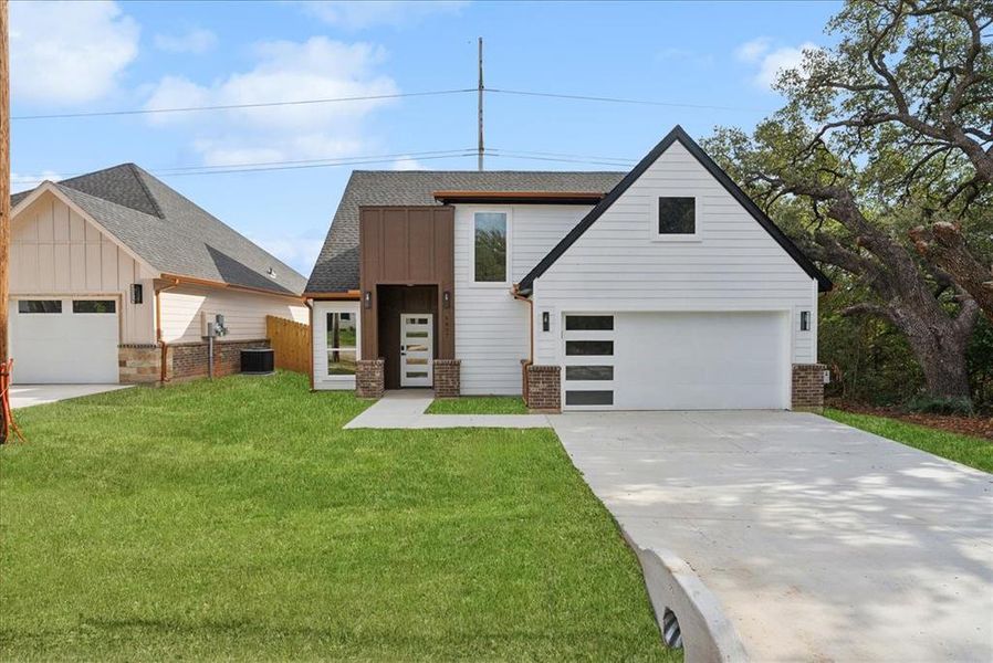 View of front of home featuring central air condition unit, a front yard, and a garage