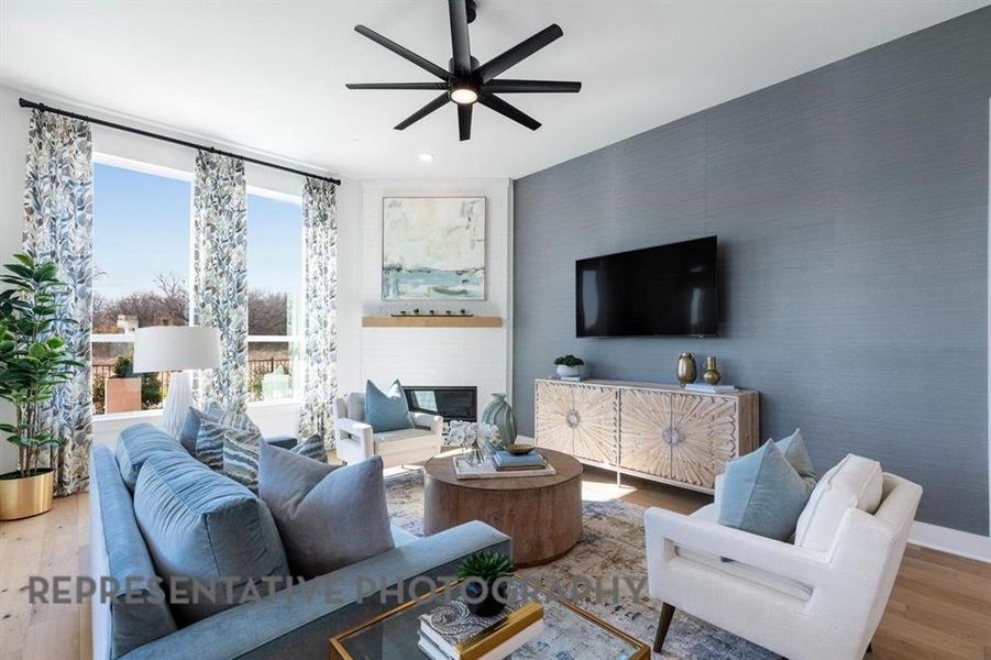 Living area with wood finished floors, a glass covered fireplace, a ceiling fan, and wallpapered walls