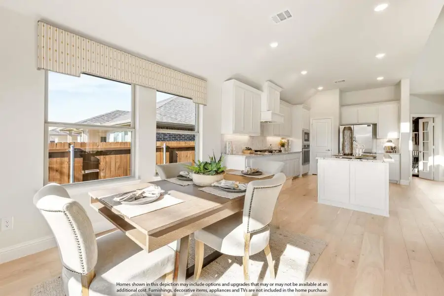Open dining area with wood table flowing into white kitchen with island and hardwood floors