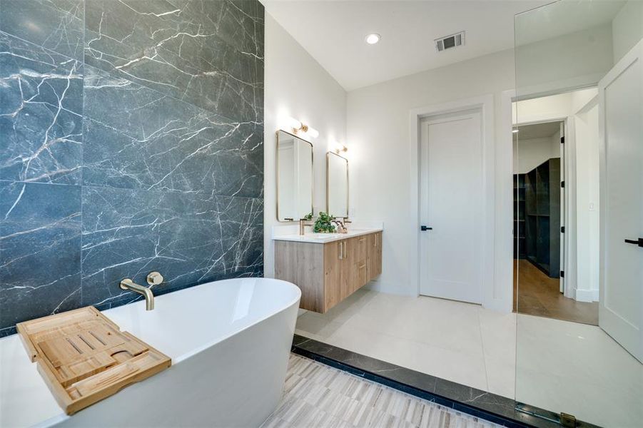 Bathroom featuring vanity, a tub, tile patterned floors, and tile walls