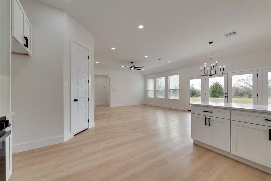 Kitchen featuring ceiling fan with notable chandelier, light hardwood / wood-style floors, hanging light fixtures, and white cabinets