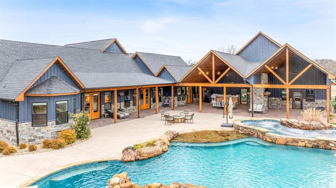 View of pool with a patio and a pool with connected hot tub