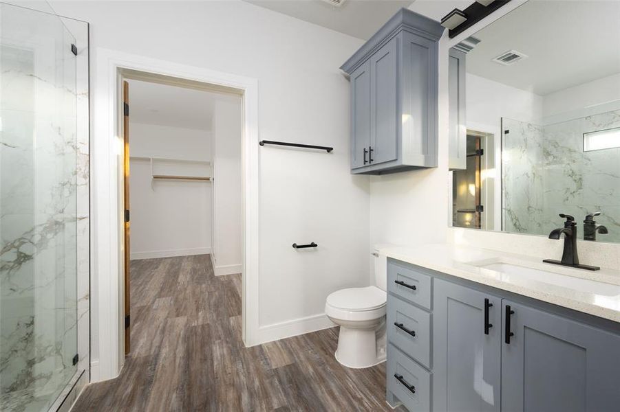 Bathroom featuring a marble finish shower, vanity, a walk in closet, and dark wood-type flooring