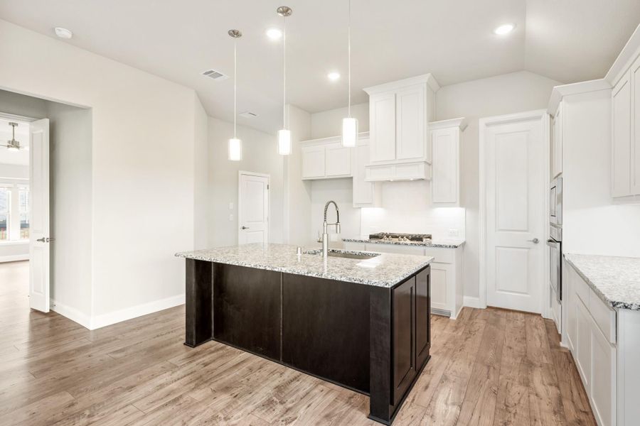 Kitchen with white cabinets, granite island with sink, pendant lights, and hardwood floors Kitchen with white cabinets, granite island with sink, pendant lights, and hardwood floors