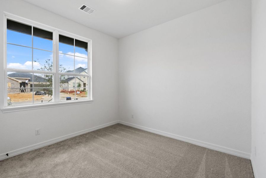 A welcoming second bedroom with large windows and comfortable plush flooring.