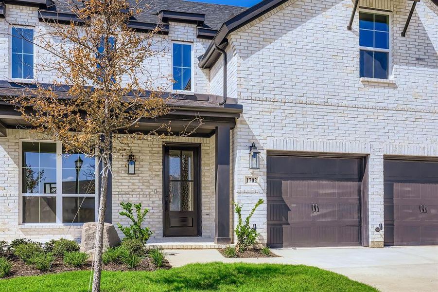 Entrance to property with brick siding, driveway, and an attached garage