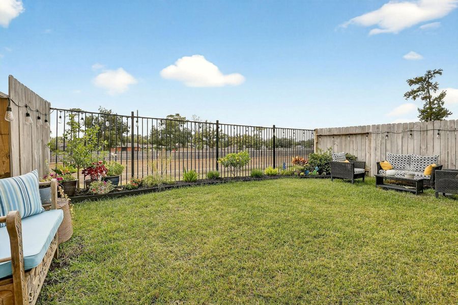 Beautifully maintained lawn accented by planters, colorful flowers, and privacy fencing, offering a cozy retreat feel. Beautifully maintained lawn accented by planters, colorful flowers, and privacy fencing, offering a cozy retreat feel.