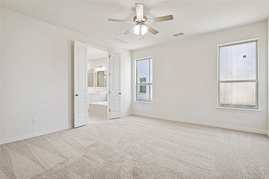 Unfurnished bedroom with light colored carpet, a ceiling fan, and connected bathroom