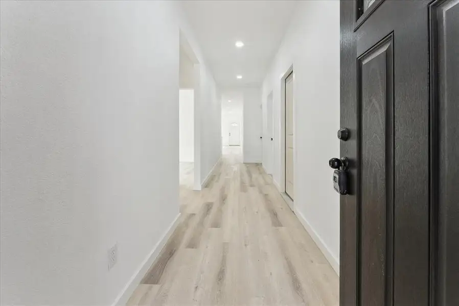 Hallway featuring light wood-type flooring, baseboards, and recessed lighting