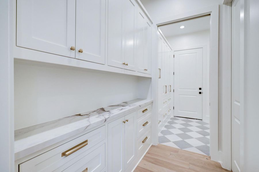 Large mud room boasts gold accents and features ample cabinets and storage. *Previous Project*
