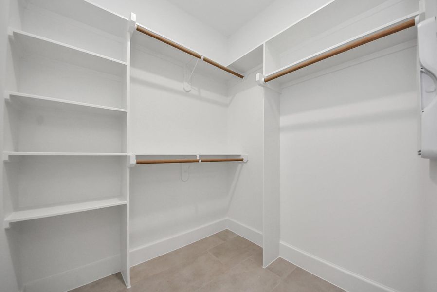 Experience this spacious walk-in closet with thoughtfully designed shelves and hanging rods. Its clean lines and neutral tones make organization effortless while maintaining a modern aesthetic.