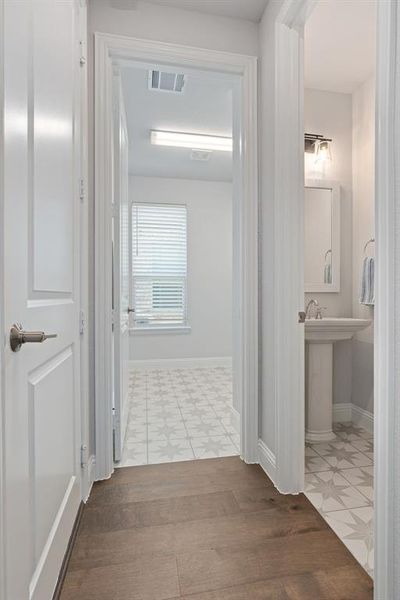 Hallway off front entry leading to a half bath and Laundry room with built in cabinetry