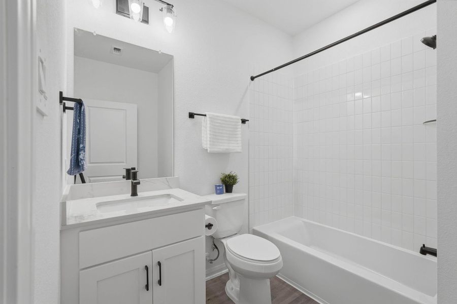 A fresh, modern bathroom features a sleek vanity, black fixtures, and a tiled tub-shower combo—clean, functional, and inviting.