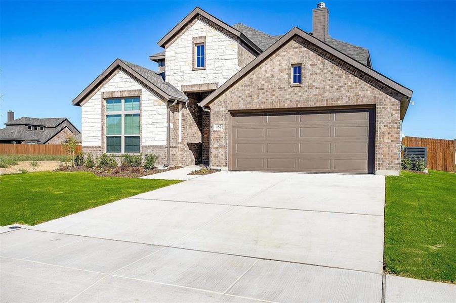 View of front facade featuring a garage and a front lawn