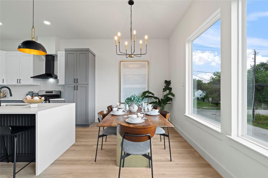 Drenched in natural light, the dining space is anchored by large picture windows and a statement chandelier—perfect for intimate dinners or lively gatherings.