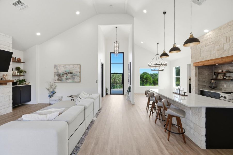 Vaulted ceilings and wide-plank wood flooring define this open-concept main living and dining zone.