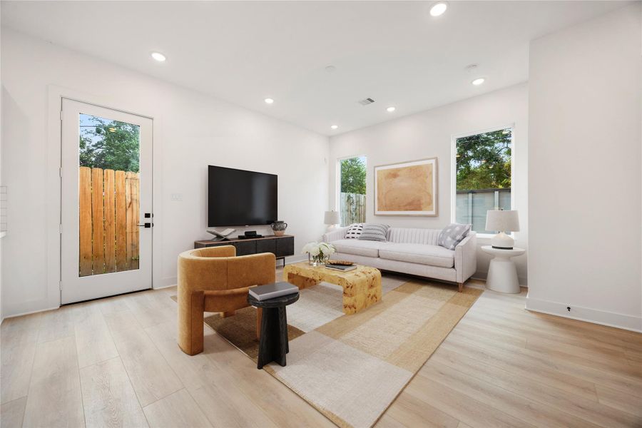 The bright and airy Living Room offers a spacious layout ideal for both relaxing evenings and lively gatherings. Designed for comfort and connection, it features vinyl plank flooring, large windows, high ceilings with recessed lighting, and an access door to the outdoor space. *Virtually Staged