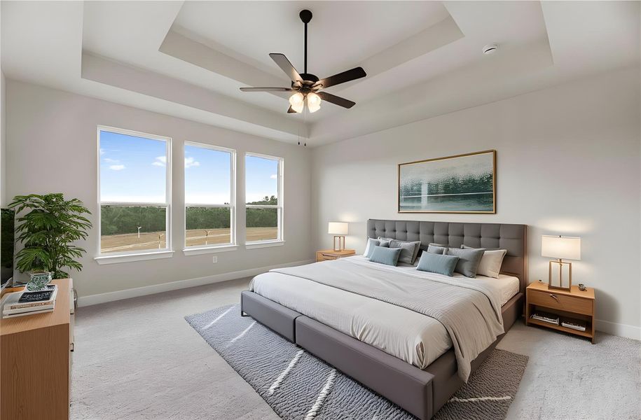 Bedroom featuring a raised ceiling, ceiling fan, and light carpet