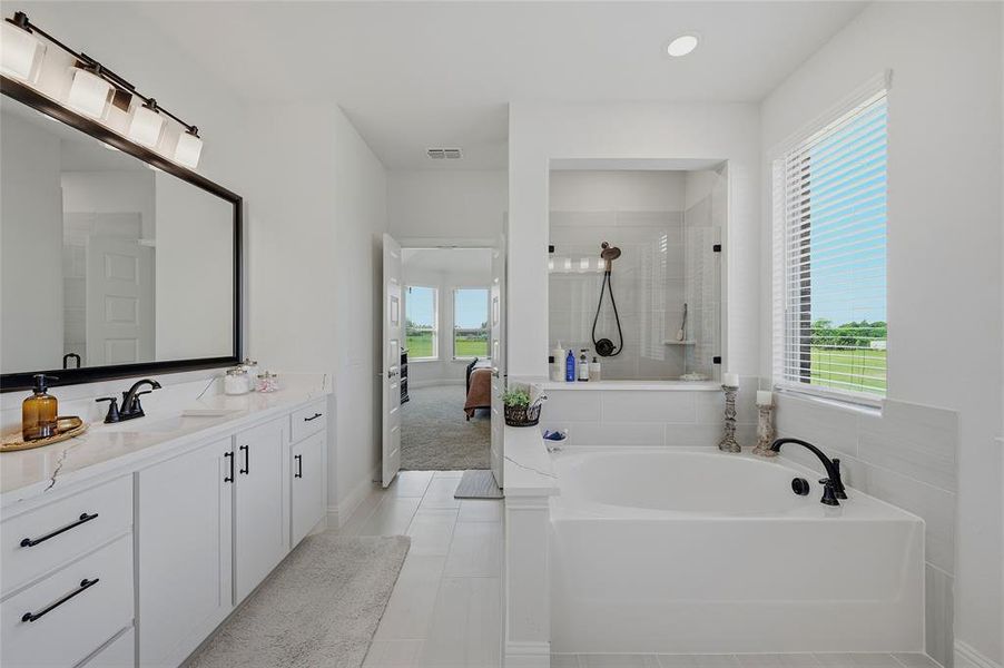 Bathroom featuring a dual vanity with white cabinetry and dark hardware, a rectangular undermount sink, and a large framed mirror