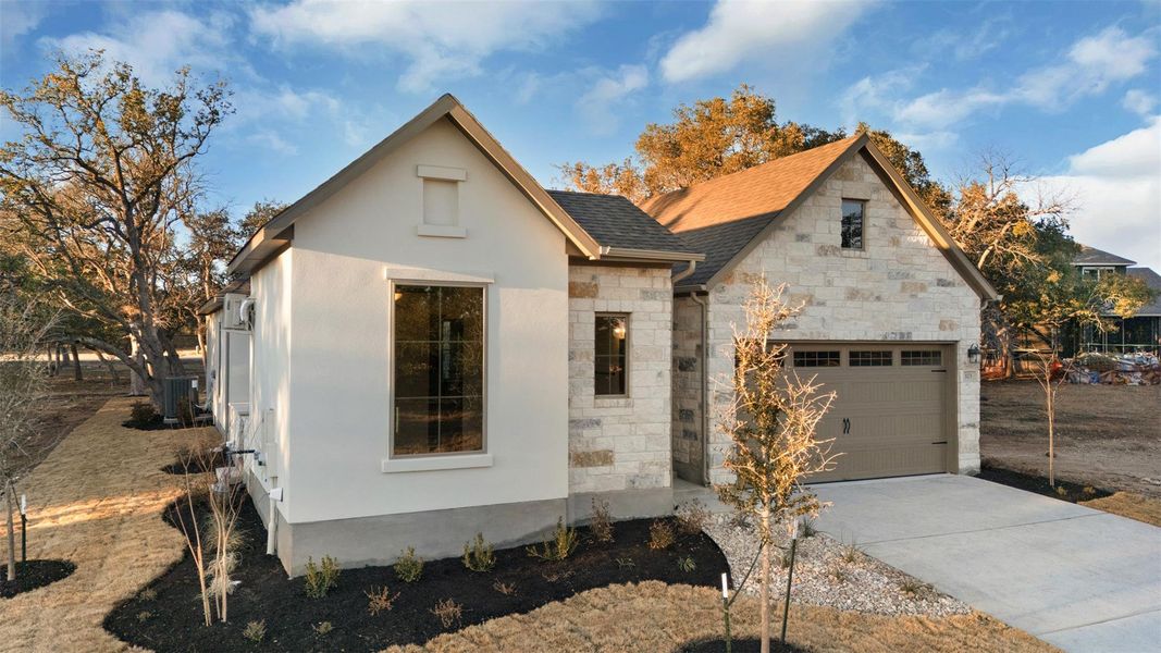View of front facade with stone siding, concrete driveway, stucco siding, and a shingled roof