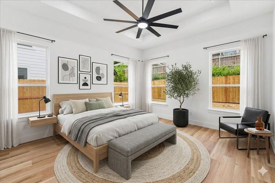 Virtually Staged - Spacious bedroom with wood-finish flooring, a tray ceiling, and a contemporary ceiling fan Virtually Staged - Spacious bedroom with wood-finish flooring, a tray ceiling, and a contemporary ceiling fan