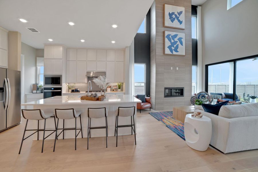 Kitchen featuring an island with sink, open floor plan, a breakfast bar area, stainless steel appliances, and a high ceiling