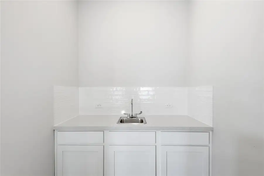 Bar featuring white cabinets, backsplash, and light stone counters Bar featuring white cabinets, backsplash, and light stone counters