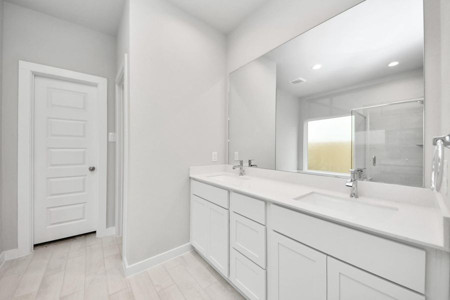 Escape to a spa-like oasis in this primary bathroom. Enjoy a walk-in shower with tile surround, a separate garden tub with custom detailing, and an elegant vanity featuring light countertops, modern hardware, and beautiful vanity lights. Experience luxury and relaxation in every detail. Sample photo of completed home with similar floor plan. Actual colors and selections may vary. Escape to a spa-like oasis in this primary bathroom. Enjoy a walk-in shower with tile surround, a separate garden tub with custom detailing, and an elegant vanity featuring light countertops, modern hardware, and beautiful vanity lights. Experience luxury and relaxation in every detail. Sample photo of completed home with similar floor plan. Actual colors and selections may vary.