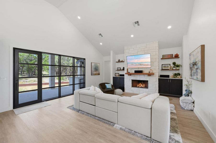 Vaulted ceilings and a stone fireplace define this inviting living space anchored by glass doors.