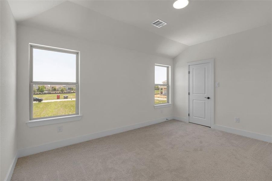 Carpeted room featuring a vaulted ceiling and two windows with white trim