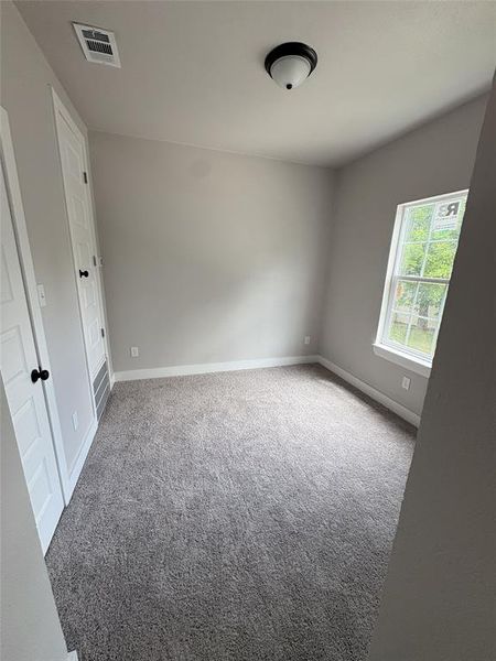 Neutral-toned room featuring a single window, two panel doors, and a ceiling-mounted light fixture Neutral-toned room featuring a single window, two panel doors, and a ceiling-mounted light fixture