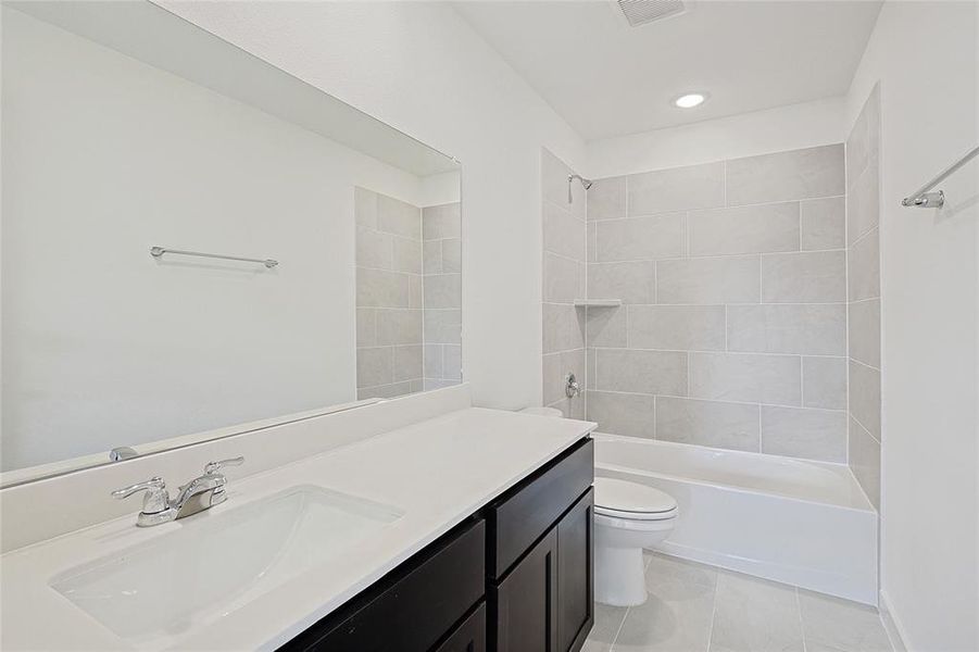 Full bathroom featuring tile patterned flooring, toilet, vanity, and tiled shower / bath