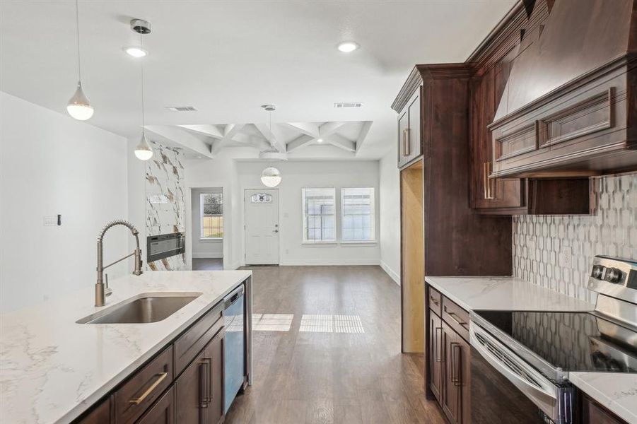 Kitchen featuring coffered ceiling, sink, hanging light fixtures, beamed ceiling, and stainless steel appliances