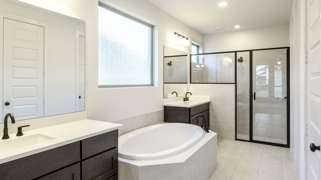 Full bath with a shower stall, a garden tub, two vanities, light tile patterned floors, and recessed lighting Full bath with a shower stall, a garden tub, two vanities, light tile patterned floors, and recessed lighting
