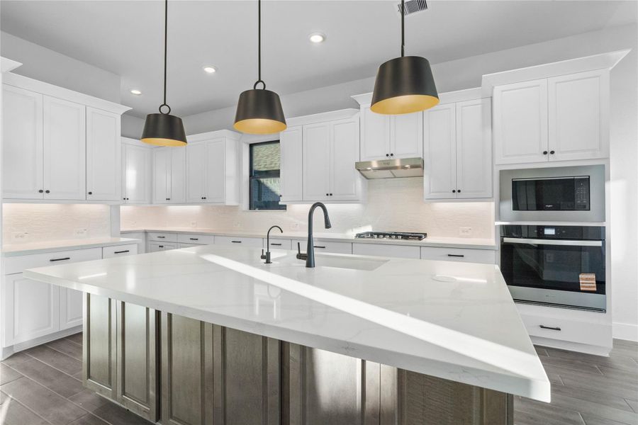 The stunning and generously sized center island features a breakfast bar, perfect for casual dining and entertaining. The island is beautifully designed with pristine quartz countertop and elegant pendant lights.