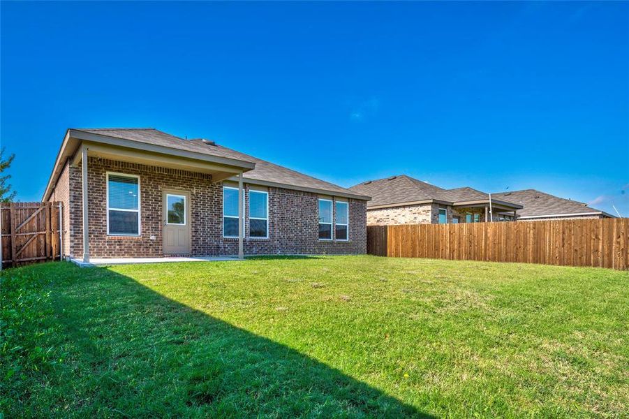 Back of property featuring brick siding, a covered patio area, and a spacious fenced backyard. Back of property featuring brick siding, a covered patio area, and a spacious fenced backyard.