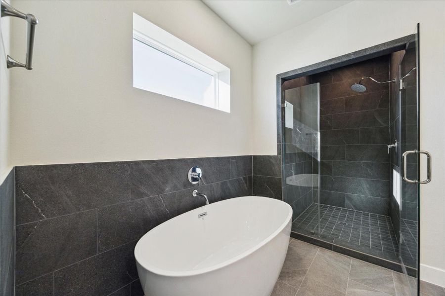 The spa-inspired primary bath features a freestanding soaking tub and a sleek glass-enclosed shower, creating a relaxing retreat at the end of the day.
