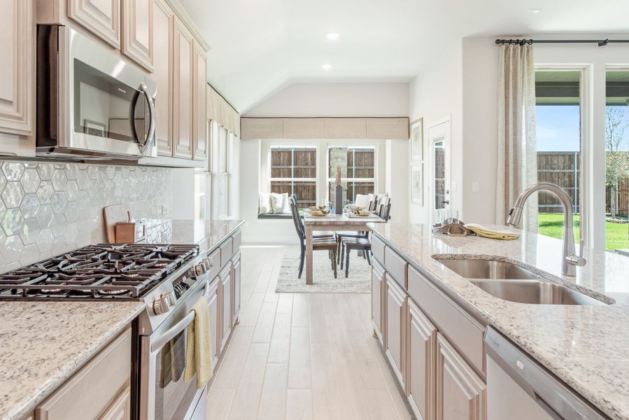 Galley kitchen with granite countertops, gas range, hexagon tile backsplash, and stainless steel appliances opening to dining area Galley kitchen with granite countertops, gas range, hexagon tile backsplash, and stainless steel appliances opening to dining area