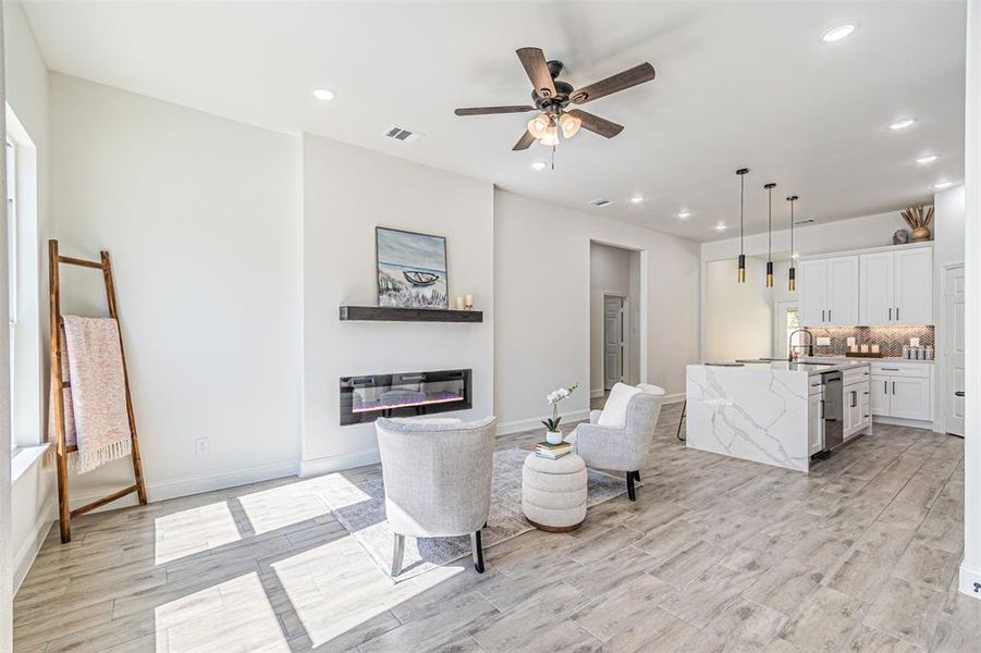 Living area featuring recessed lighting, a ceiling fan, a glass covered fireplace, and light wood-type flooring